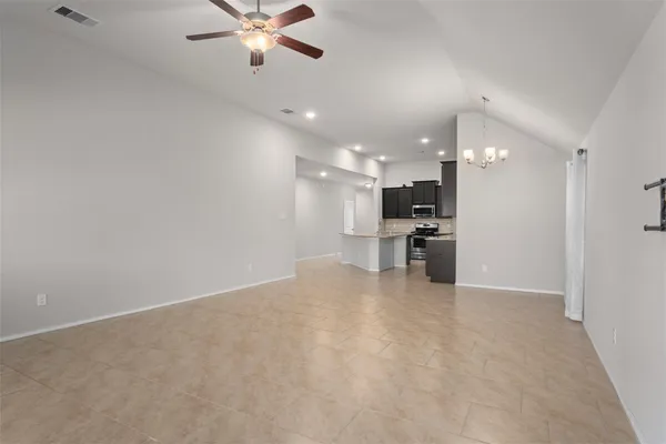 a view of an empty room with a chandelier fan