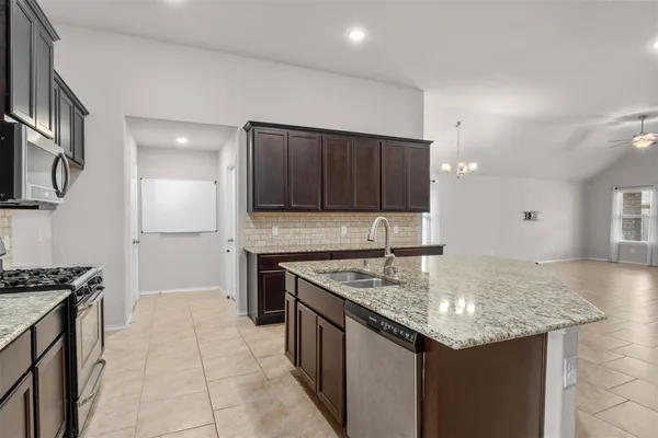 a kitchen with stainless steel appliances granite countertop a sink a stove a microwave and a refrigerator