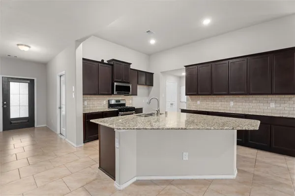 a kitchen with stainless steel appliances granite countertop a stove top oven a sink and a microwave