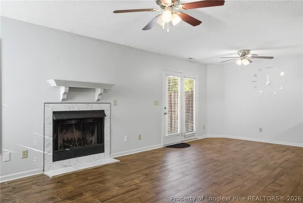 an empty room with chandelier fan and fireplace