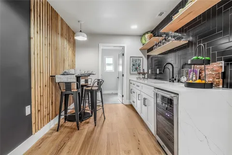 a large white kitchen with wooden floor and stainless steel appliances