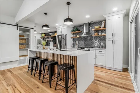 a kitchen with stainless steel appliances kitchen island granite countertop a table chairs and a refrigerator