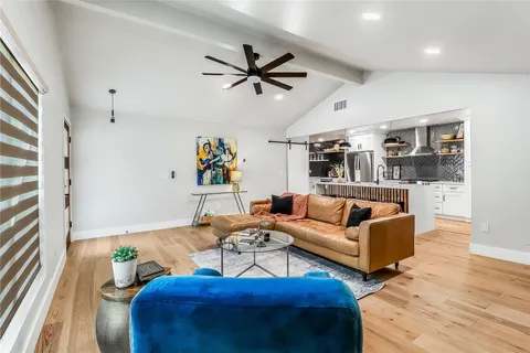 a living room with furniture kitchen view and a wooden floor