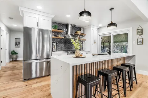 a kitchen with stainless steel appliances a dining table chairs refrigerator and stove