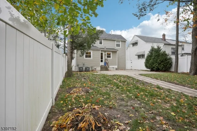 a view of a house with a small yard and large tree