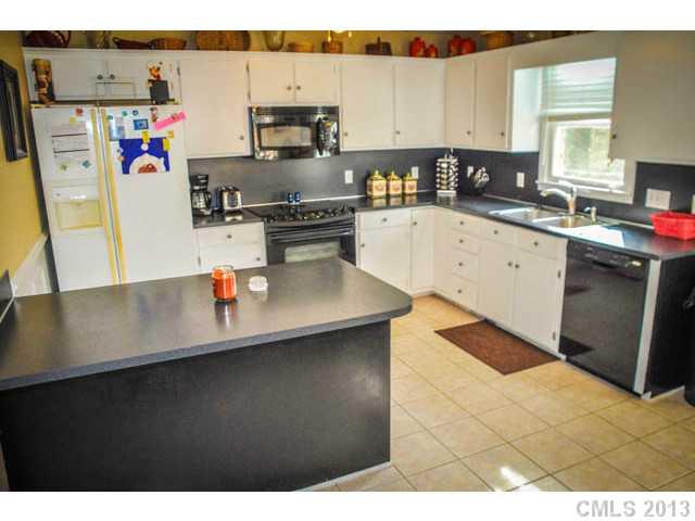 4915 Griffith Road Monroe, NC 28112 - Photo 10 of 16 a kitchen with stainless steel appliances a sink a stove a refrigerator white cabinets a dining table and chairs