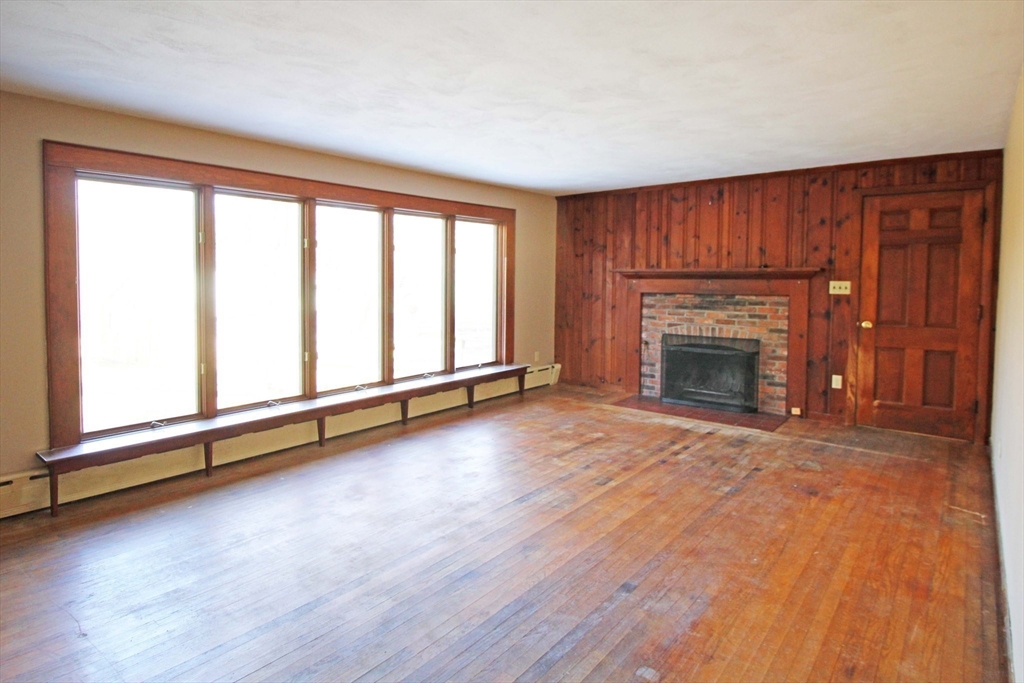 128 Amherst Road Pelham, MA 01002 - Photo 3 of 31 an empty room with wooden floor fireplace and windows