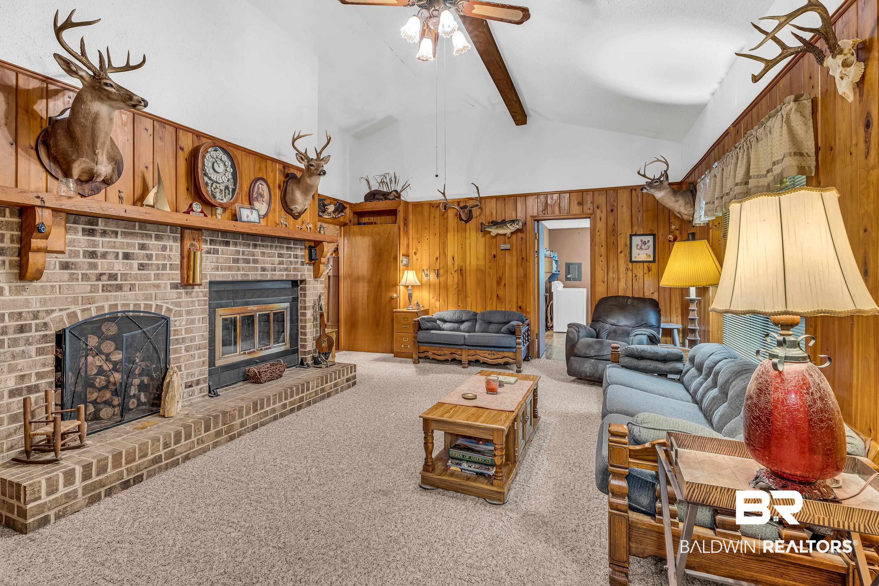 72075 Highway 59 Little River, AL 36550 - Photo 8 of 40 Living area featuring wood walls, beam ceiling, carpet floors, high vaulted ceiling, and a fireplace