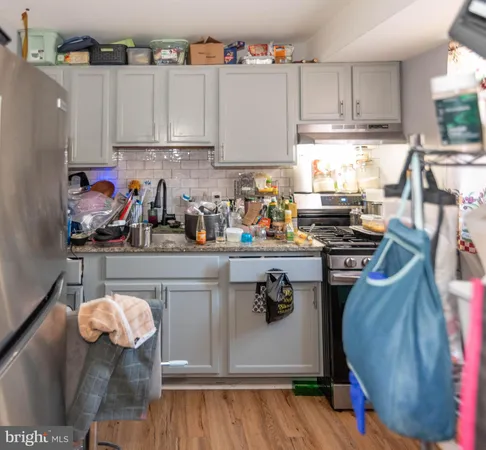 a kitchen with stainless steel appliances granite countertop a sink dishwasher a stove a refrigerator and microwave with wooden floor