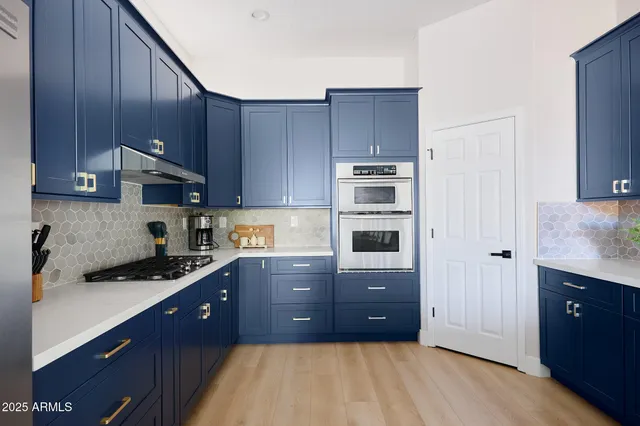 a kitchen with stainless steel appliances granite countertop a stove a sink and a refrigerator with wooden cabinets