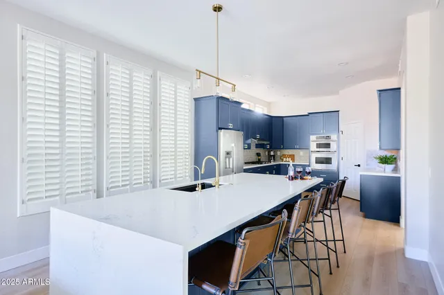 a kitchen with stainless steel appliances a table and chairs in it