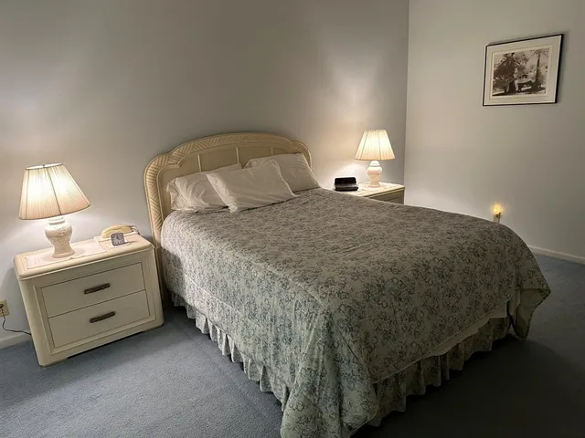a bedroom with a bed and a lamp on dresser