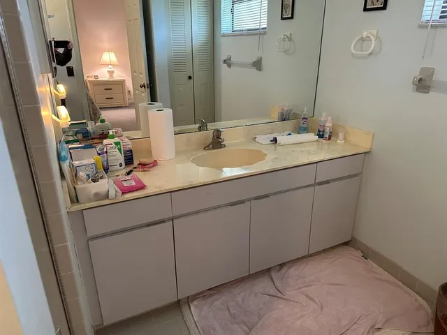 a bathroom with a sink and a mirror white cabinets
