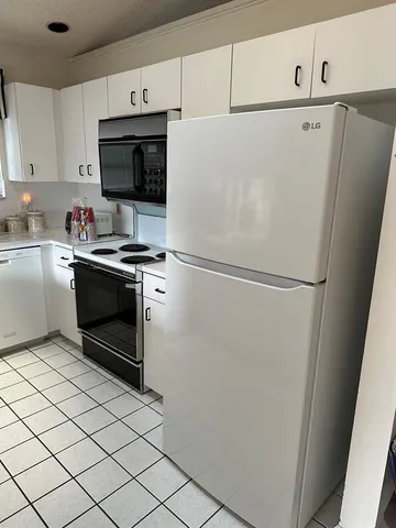 a white refrigerator freezer and a stove sitting inside of a kitchen with granite countertop stainless steel appliances