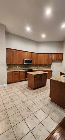 a kitchen with stainless steel appliances granite countertop a refrigerator and a stove top oven