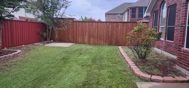 a view of a backyard with plants and wooden fence