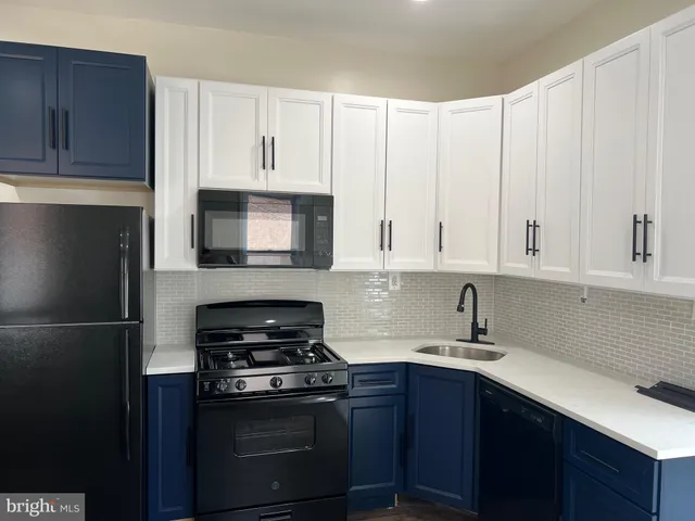 a view of a kitchen with a refrigerator a stove top oven and wooden floor