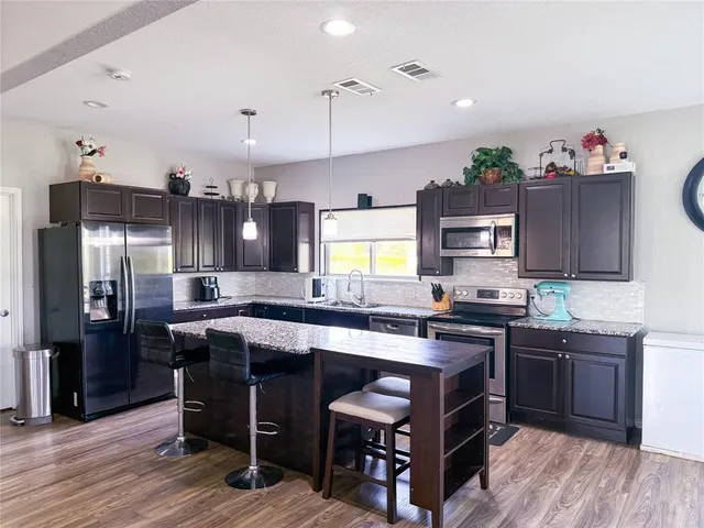 a kitchen with kitchen island granite countertop a sink stove and refrigerator