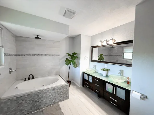 a spacious bathroom with a double vanity sink a mirror and bathtub