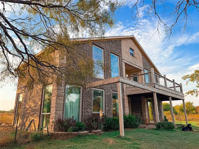 a view of a white house with a big yard and large trees