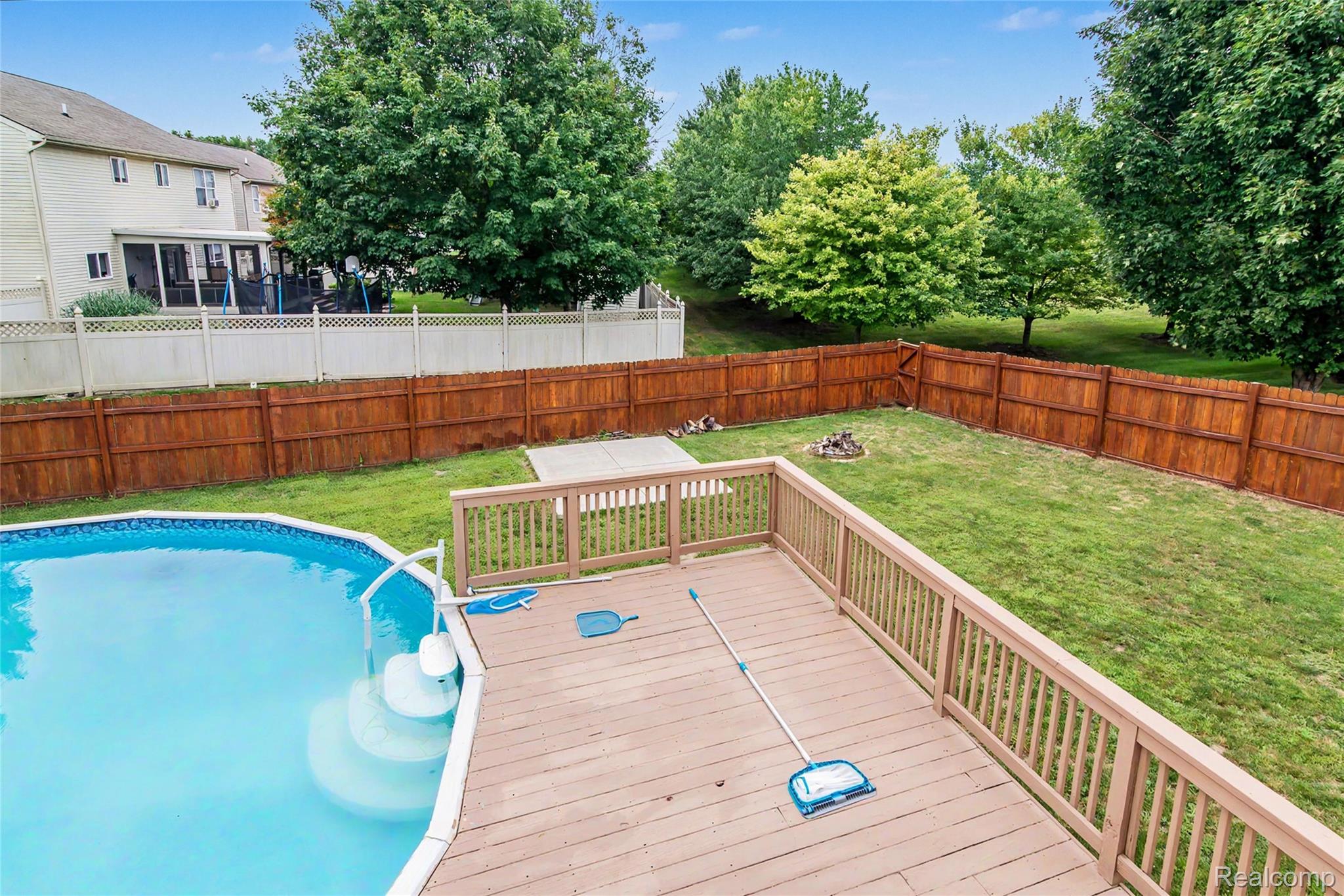486 Sweet Briar Ridge Linden, MI 48451 - Photo 12 of 69 Expansive backyard featuring a large swimming pool, wooden deck, manicured lawn, and privacy fencing