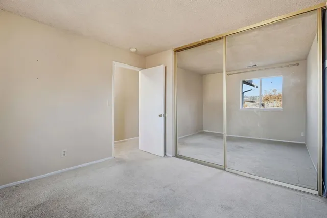 an empty room with closet and a ceiling fan