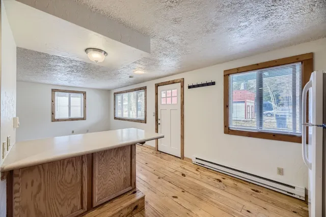 a living room with stainless steel appliances wooden floor and large window