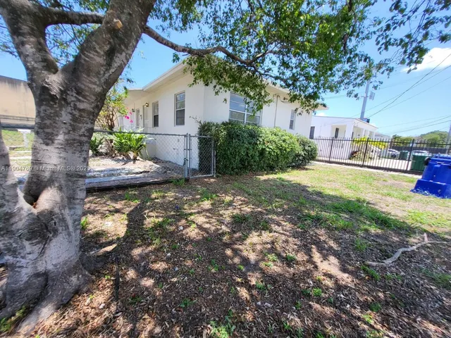 a backyard of a house with plants and large tree