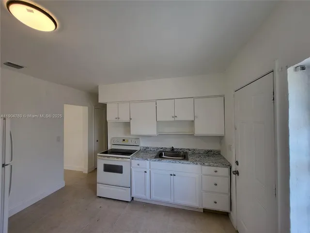 a kitchen with granite countertop white cabinets and stainless steel appliances