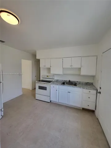 a kitchen with granite countertop a white stove and cabinets