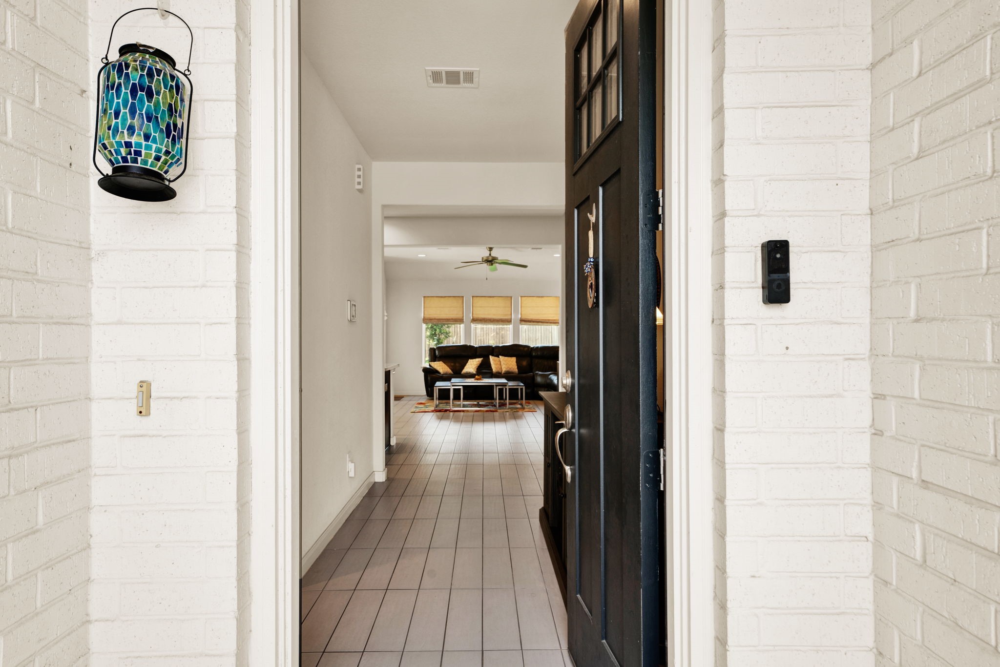 2503 Hagerman Road Conroe, TX 77384 - Photo 7 of 43 The photo shows an inviting entryway with a black door opening into a bright, open-plan living area. The interior features light-colored walls and sleek flooring. A modern light fixture and a cozy seating area are visible in the background, offering a welcoming and stylish first impression.