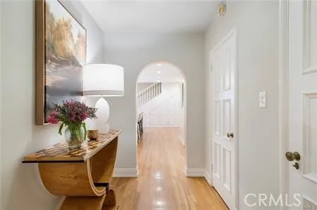 a view of a hallway with wooden floor table and chairs