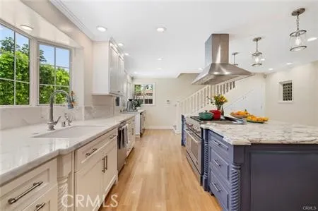 a kitchen with granite countertop a sink stainless steel appliances and living room view