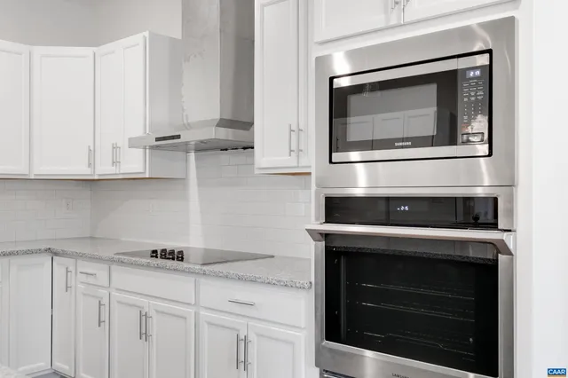 a kitchen with stainless steel appliances granite countertop white cabinets and stove