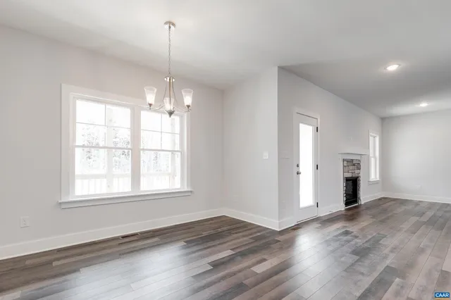 an empty room with wooden floor cabinet and windows