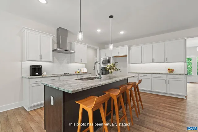 a kitchen with stainless steel appliances granite countertop a sink a stove a refrigerator and white cabinets