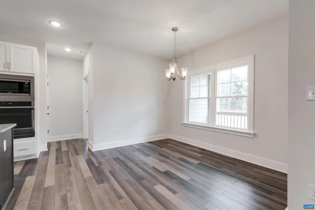 an empty room with wooden floor cabinet and windows