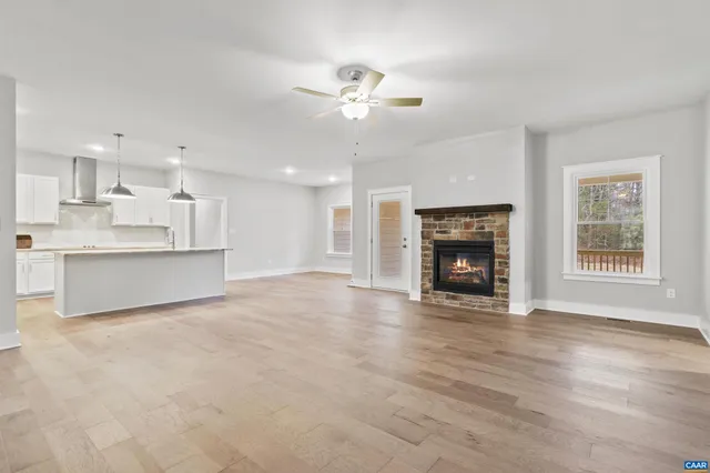 a view of a livingroom with a fireplace a ceiling fan and windows