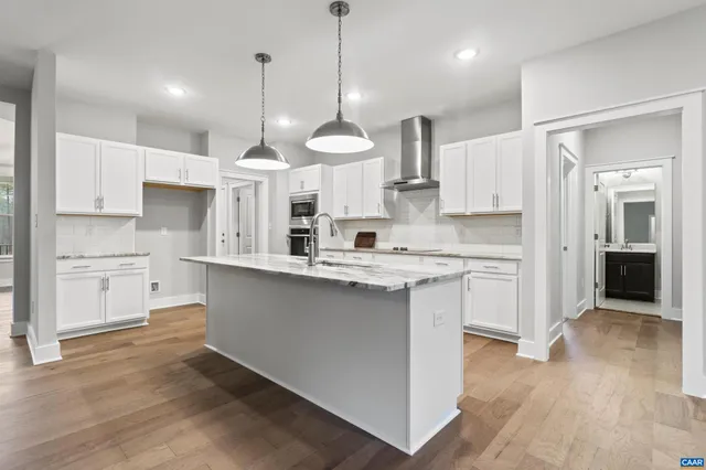 a kitchen with stainless steel appliances granite countertop a stove a sink dishwasher a refrigerator and white cabinets with wooden floor