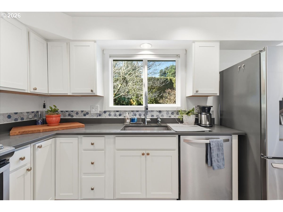 10339 Southwest 40th Avenue Portland, OR 97219 - Photo 12 of 37 a kitchen with stainless steel appliances granite countertop a sink a refrigerator a window and white cabinets