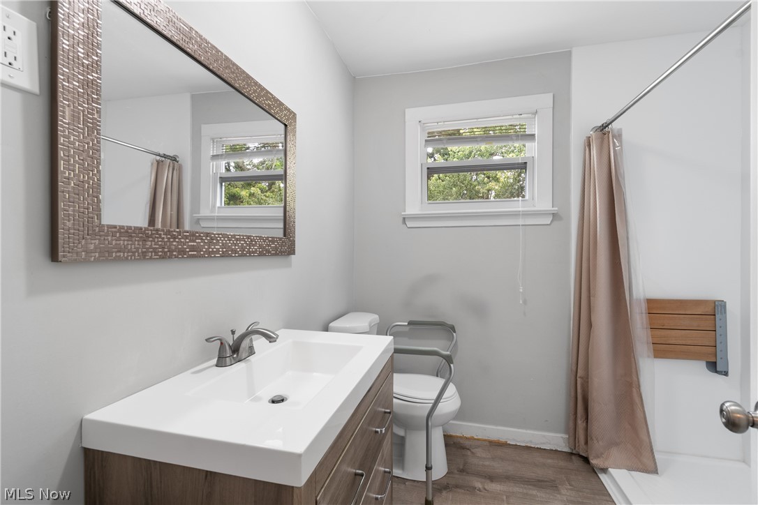 5768 Nolley Road Akron, OH 44319 - Photo 18 of 38 Bathroom featuring a modern vanity with integrated sink, brushed nickel faucet, large framed mirror, and wood-finish flooring