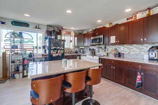 a kitchen with stainless steel appliances granite countertop a table chairs sink and cabinets