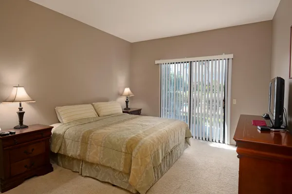 a bedroom with a bed and a flat tv screen on a dresser