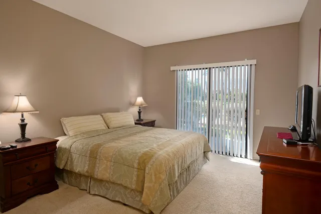 a bedroom with a bed and a flat tv screen on a dresser