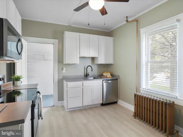 a kitchen with granite countertop white cabinets a sink a window and appliances