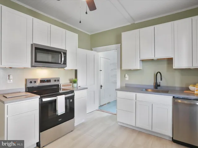 a kitchen with stainless steel appliances granite countertop white cabinets a sink a stove a microwave and a refrigerator