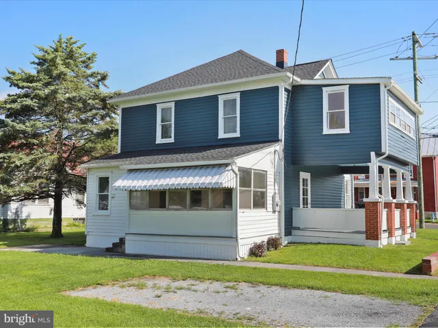 a front view of a house with a garden and trees