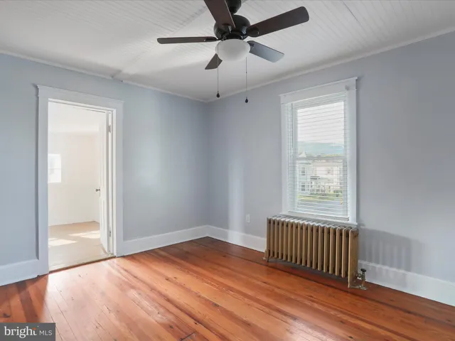 an empty room with wooden floor fan and windows