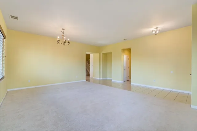 a view of an empty room with a chandelier fan