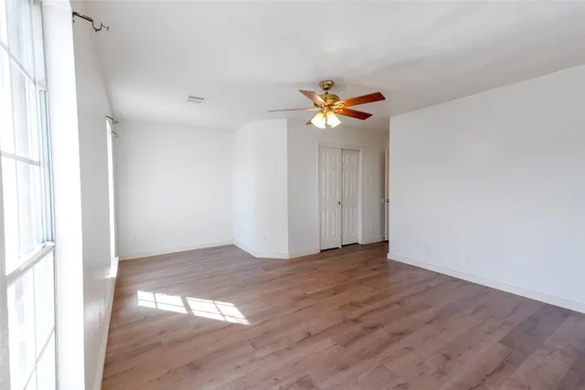 an empty room with wooden floor and chandelier fan